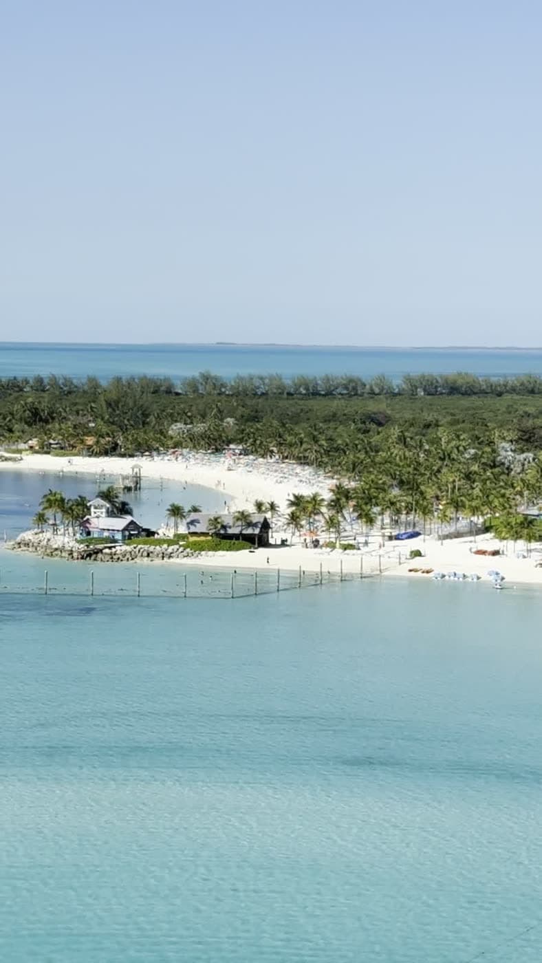 A white-sand private island beach and turquoise lagoon seen from a ship