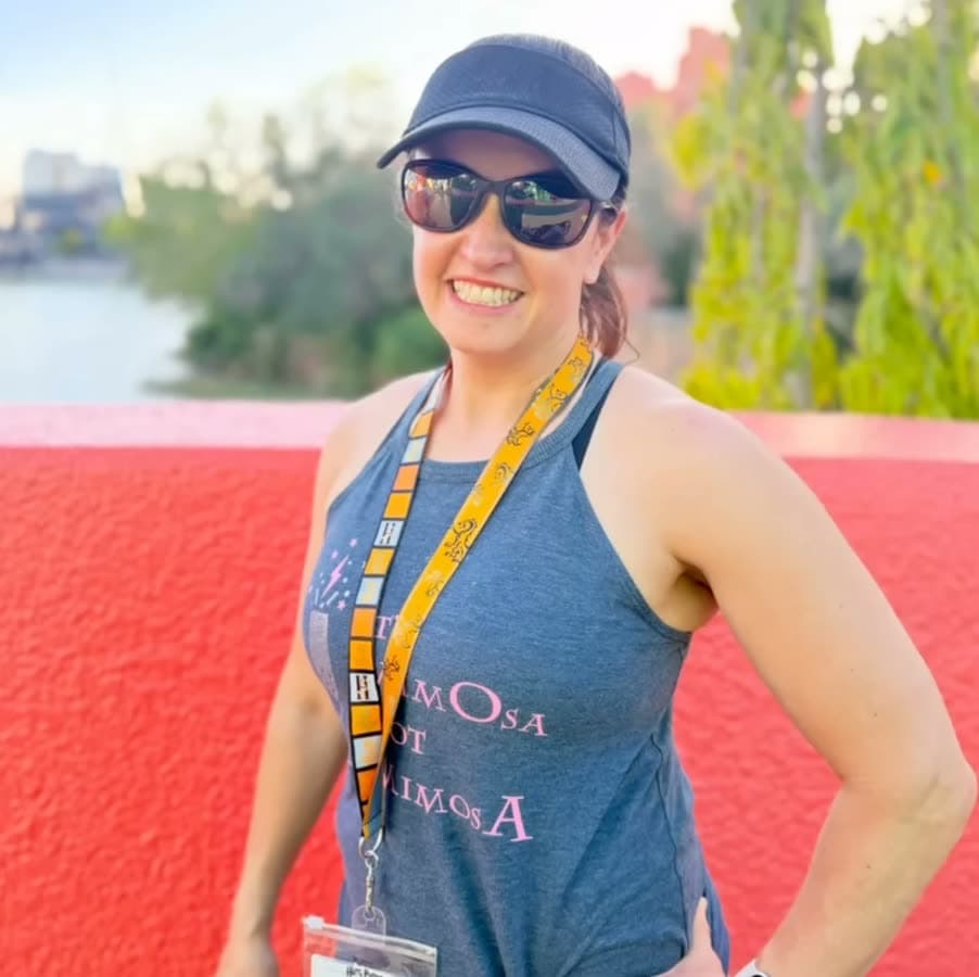 Nikki smiling in a visor and sunglasses at a theme park